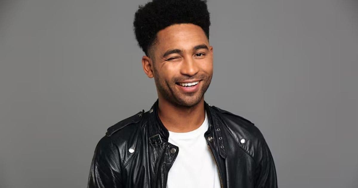 Young smiling african man in black leather jacket winks one eye, looking